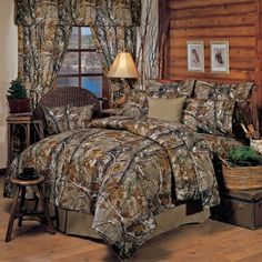 the bed is made up with camo comforter and pillows, along with two lamps