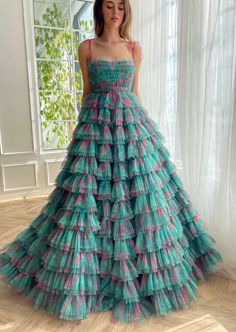 This show-stopping dress encapsulates the perfect blend of vibrant charm and timeless elegance, thoughtfully crafted from patterned green-pink tulle that evokes a sense of whimsical sophistication. The dress flaunts a flattering bustier silhouette, enhanced by supportive corsetry boning that effortlessly sculpts and enhances the wearer's figure. The draped bodice introduces a romantic allure, seamlessly transitioning into a cinched waist that further accentuates the body's natural curves. The dr Whimsical Multicolor Ruffled Dress, Whimsical Multicolor Princess Dress With Ruffles, Teuta Matoshi Lavender, Teuta Matoshi Pink Dress, Teuta Matoshi Butterfly Dress, Teuta Matoshi Dresses, Matoshi Dress, Yule Ball Outfits, Organza Dresses