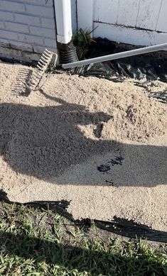 the shadow of a person standing in front of a house with a shovel and rake