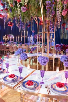 the table is set with purple and red flowers, plates and silverware on it