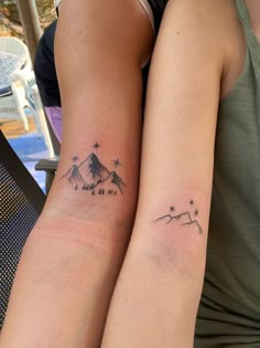 two people with matching tattoos on their arms, one has a mountain and the other has stars