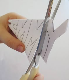 someone is cutting out a paper airplane with scissors