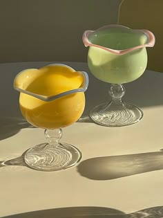 there are two glasses that have different colored drinks in them, one is yellow and the other is green