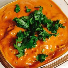 a bowl filled with red sauce and garnished with cilantro