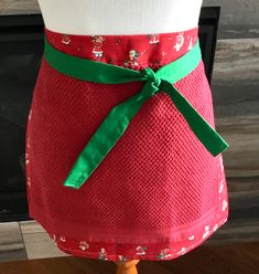 a woman's red apron with green ribbon on it