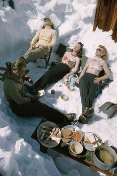 four people are sitting in the snow with food