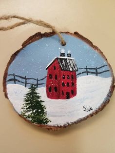 a wooden ornament with a red house painted on it's side in the snow