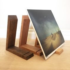 an easel with a painting on it sitting on a wooden floor next to two pieces of wood