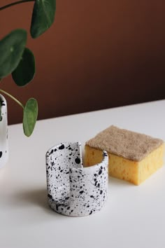 two pieces of pottery sitting on top of a table next to a potted plant