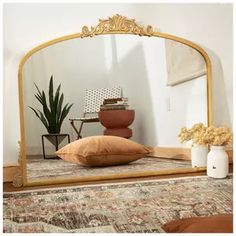 a large mirror sitting on top of a bed next to a vase filled with flowers