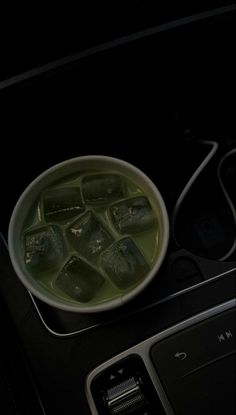 a bowl filled with green liquid sitting on top of a table next to a cell phone