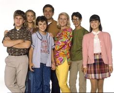 a group of people standing next to each other in front of a white background with their arms crossed