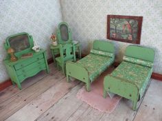 two green twin beds in a room with wooden floors and wall papered walls, one has a pink rug on the floor