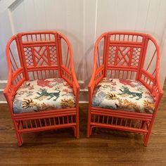 two orange chairs sitting next to each other on top of a wooden floor