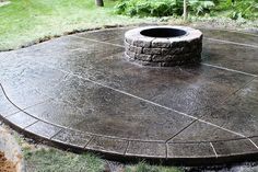 a fire pit sitting on top of a cement slab in the middle of a yard