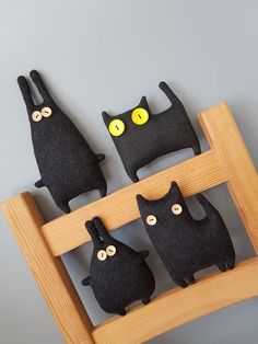 three black cats sitting on top of a wooden shelf next to each other with yellow eyes