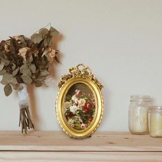 a vase filled with flowers sitting on top of a wooden shelf next to a mirror