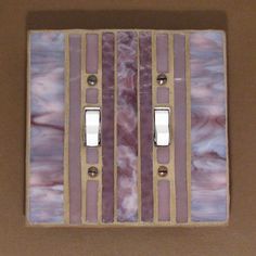 a light switch cover with purple and white stripes