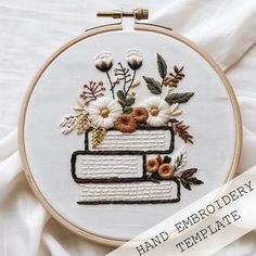 a hand embroidery pattern with flowers and leaves on white fabric, in the shape of a stack of books