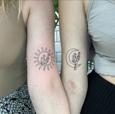 two women with matching tattoos on their arms, one has a sun and the other has a flower