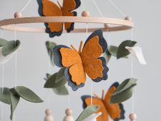 an orange and blue butterfly mobile hanging from a wooden frame