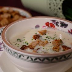 a bowl of soup with croutons and parmesan cheese on the side