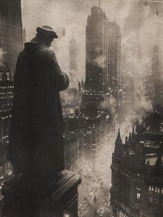 a man standing on top of a tall building in the middle of a city at night