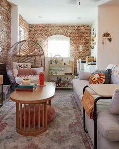 a living room filled with furniture and a brick wall behind the couches is a round coffee table