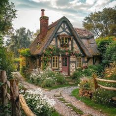 an old cottage with flowers growing on the windows