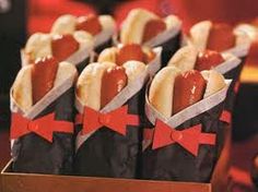 hotdogs wrapped in paper with red bows are sitting in a box on a table