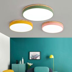 three circular lights are hanging from the ceiling in a living room with blue walls and yellow chairs