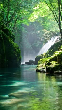 a waterfall in the middle of a forest filled with green mossy rocks and water