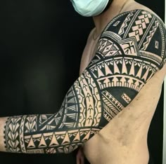 a man with a mask on his face is wearing a black and white tattoo design