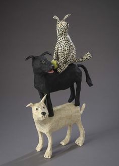 two statues of dogs on top of each other, one is riding the other dog