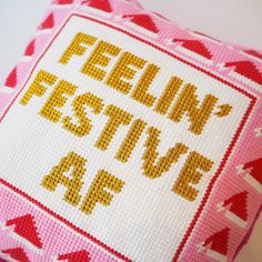 a cross stitch pillow with the words feeling festive as if it were knitted