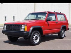 a red jeep is parked in a parking lot