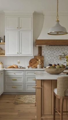 a kitchen with white cabinets and wood floors, an island countertop and two stools