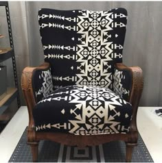 a black and white patterned chair sitting on top of a tile floor next to shelves