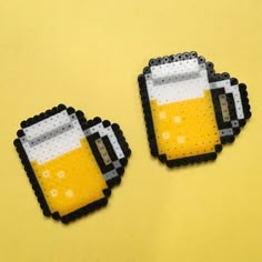 two beer mugs made out of perler beads on a yellow background with space for text