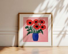 a blue vase filled with red flowers sitting on top of a wooden floor next to a wall