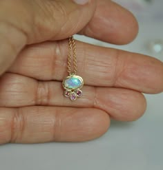 "A tiny, 14K solid gold pendant with beautiful synthetic Opal & Sapphire stones on a 14K solid gold chain. This delicate necklace resembles a flower as if a little blossom is sitting on your chest, the oval Opal is set in the center of the flower and 3 pink Sapphires are set as leaves. I pick the stones one by one, matching the light pink Sapphires color to the beautiful synthetic Opal color. You can wear this gold necklace every day as it goes well with any color of clothing and suitable fo Small Gold Pendant, Sapphire Gold Necklace, Gold Necklace With Pendant, Tiny Gold Necklace, Gold Necklace Dainty, Necklace Sapphire, Jewellery Pendant, Sapphire Stones, Jewelry To Buy