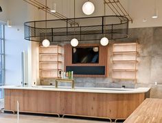 an empty kitchen with wooden counter tops and hanging lights over the island in front of it