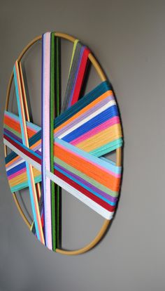 a multicolored circular object hanging on the wall in front of a gray wall