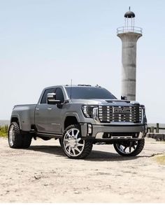 a silver truck parked in front of a light house