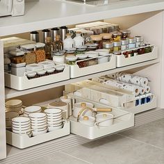 an organized kitchen drawer with dishes and utensils on the bottom shelf in front of it