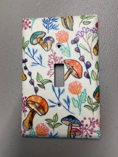 a light switch cover with mushrooms and flowers on it