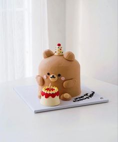 there is a cake with a teddy bear on top and a cupcake in the middle