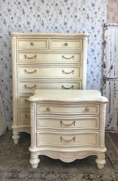 an antique white dresser and bed in a room with floral wallpaper