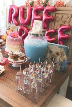 a table topped with lots of desserts and drinks next to large red letter balloons