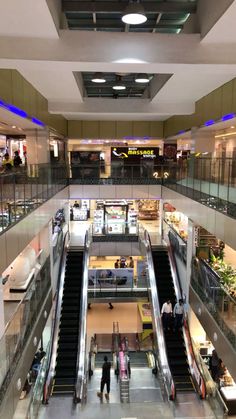 an escalator in a shopping mall with people walking up and down the stairs